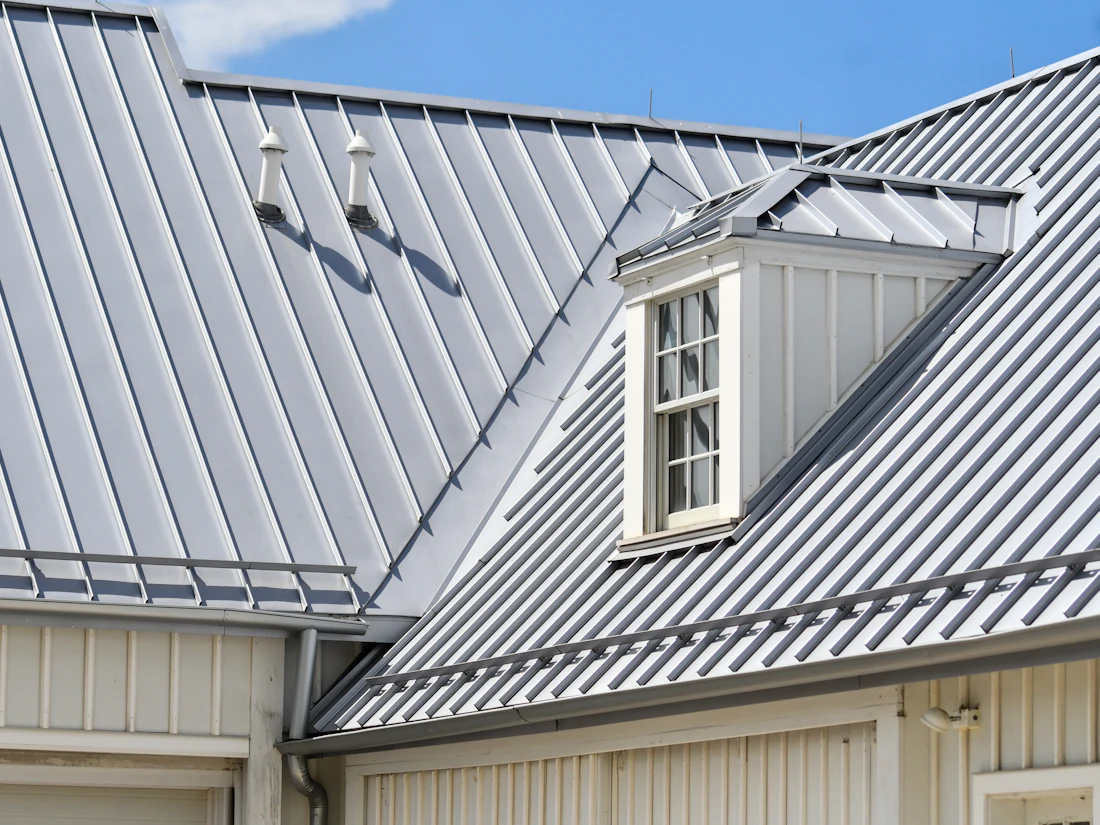 A gray standing seam metal roof with a dormer window